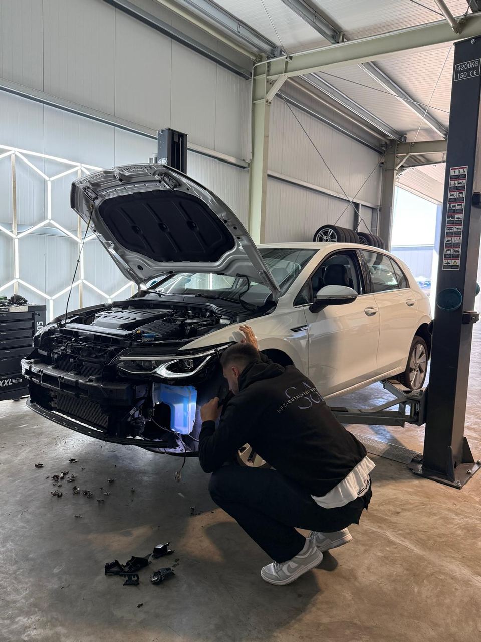 Begutachtung eines Unfallfahrzeugs auf der Hebebühne in der Werkstatt